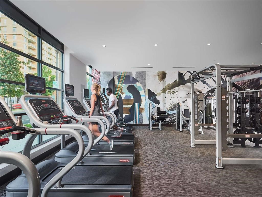 a gym with cardio machines and a mural on the wall