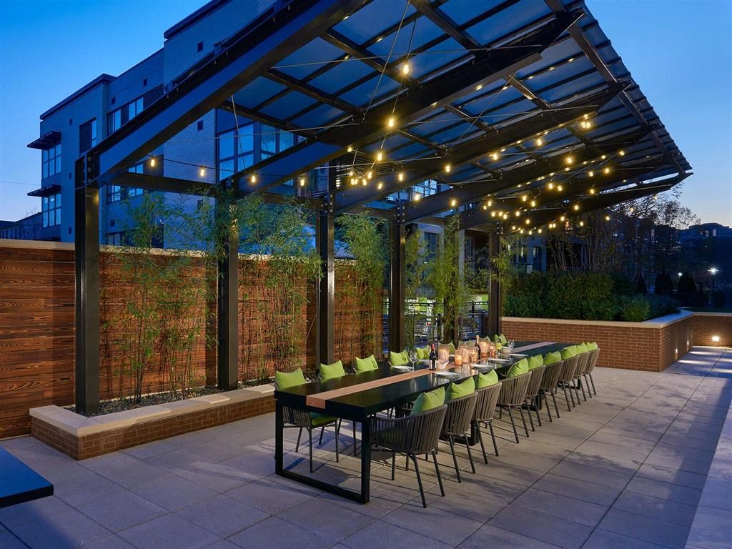 a long table and chairs under a large roof with lights