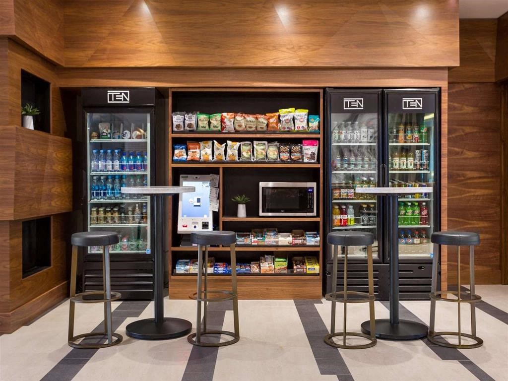 a bar with stools in front of a refrigerator and shelves of drinks