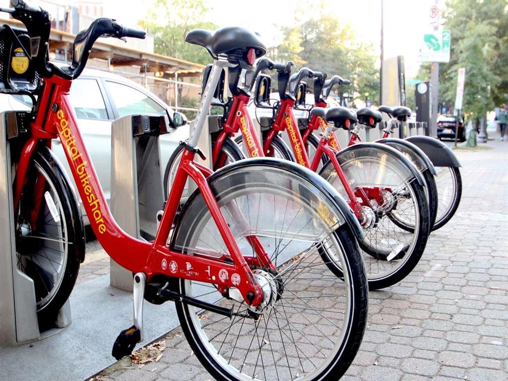 a row of red bikes parked at a bike rack