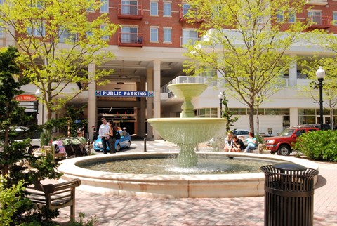 A fountain in the middle of a plaza with a sign that says