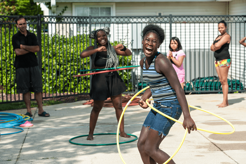 A woman is playing with a hula hoop in a driveway.