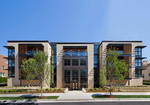 A modern building with a glass entrance and two trees in front.