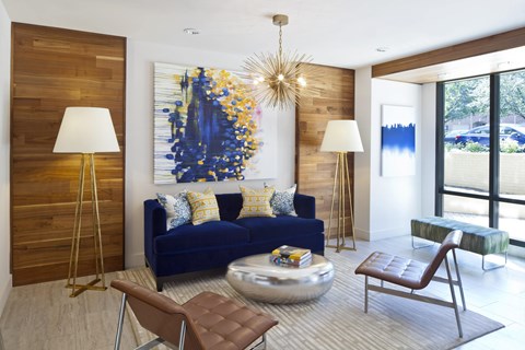 A blue couch with a yellow and blue painting behind it.