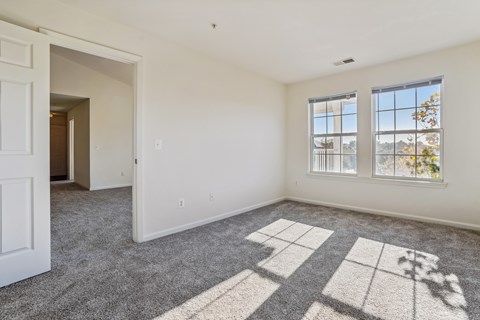 A room with a carpet and a window overlooking a city.