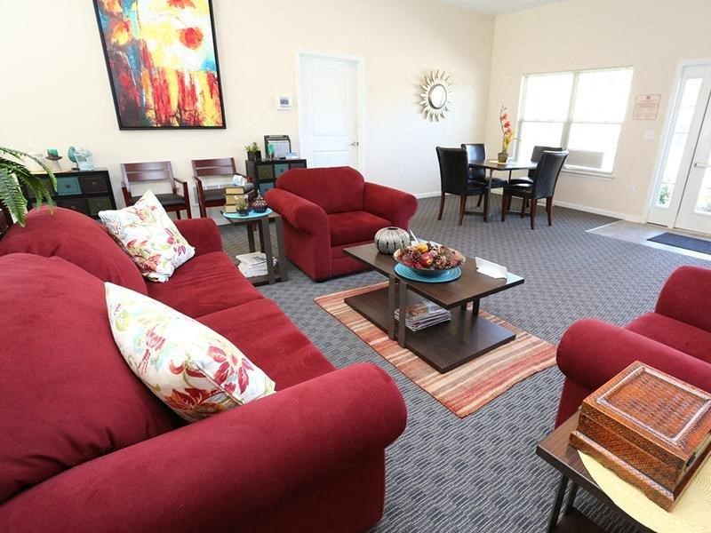 a living room with red couches and chairs and a table