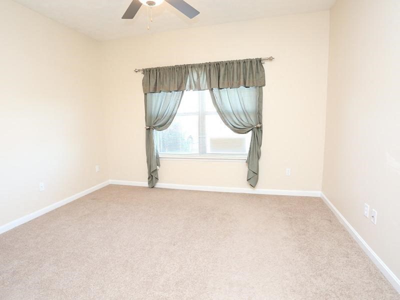 an empty living room with a window and curtains