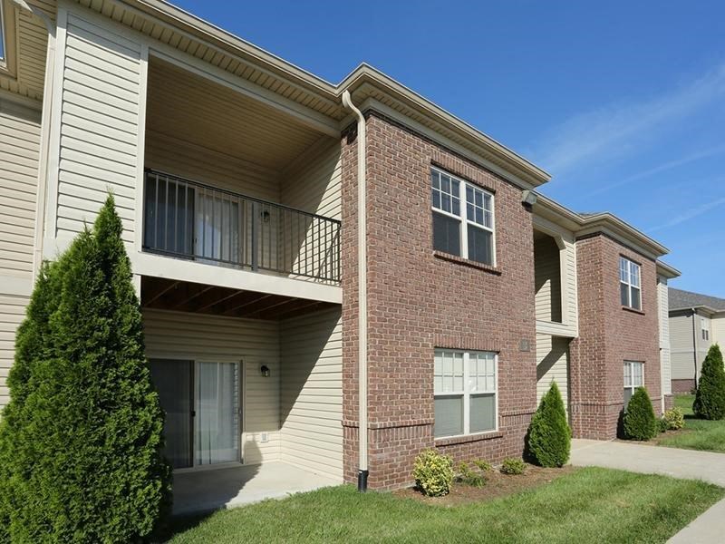 a brick apartment building with a balcony and grass
