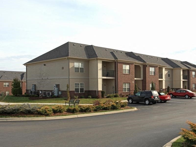 an apartment building with cars parked in a parking lot