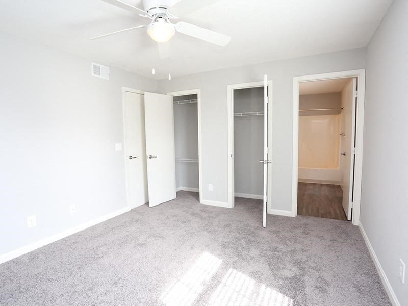 an empty living room with a ceiling fan and a closet