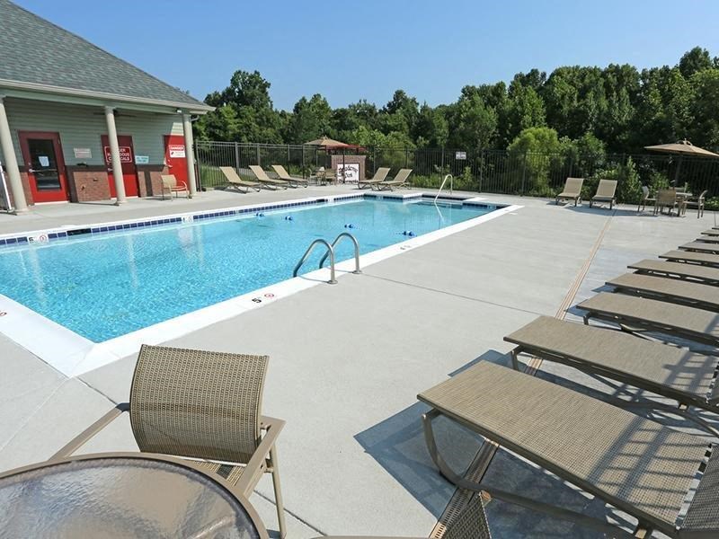 a swimming pool with chairs and tables around it