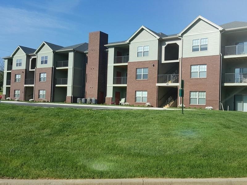 an apartment building with green grass in front of it