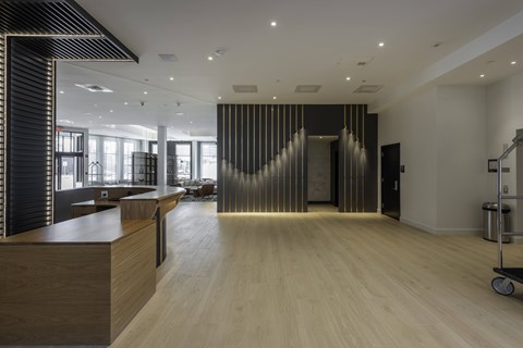 A modern office lobby with a wooden floor and a black and white striped wall.
