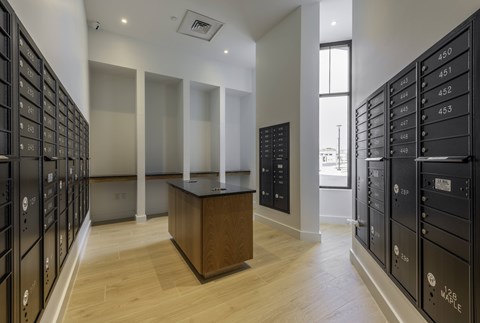 A room with a wooden table in the middle and a row of black lockers on the left side.