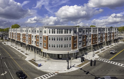 A street view of a multi-story building with cars parked on the side of the road.