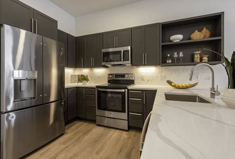 A modern kitchen with stainless steel appliances and dark wood cabinets.