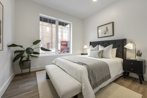 A bedroom with a large bed and a potted plant.