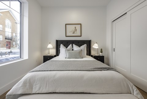 A bedroom with a large bed and a window overlooking a street.
