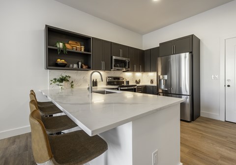 A modern kitchen with a white island and stainless steel appliances.