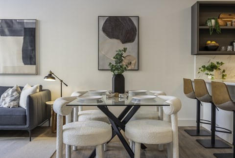 A modern dining room with a glass table and chairs.