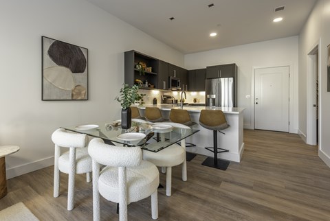 A modern dining room with a glass table and white chairs.