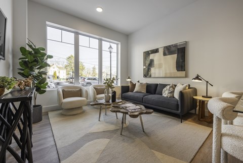 A living room with a large window, a grey sofa, and a wooden coffee table.