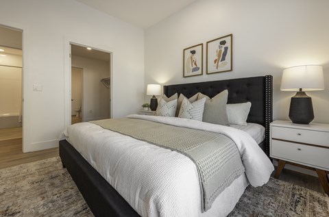 A bedroom with a large bed, two nightstands, and a painting on the wall.