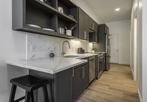 A kitchen with a white counter top and black stools.