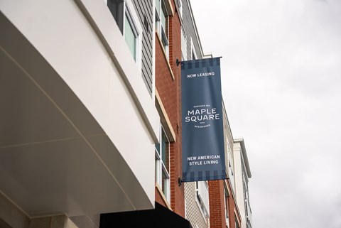 A blue banner with the words "Maple Square" hangs from a building.