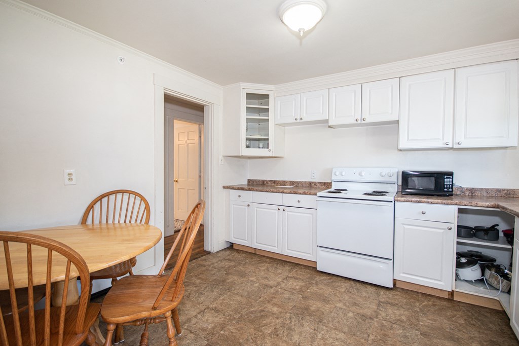 a kitchen with white cabinets and a wooden table and chairs