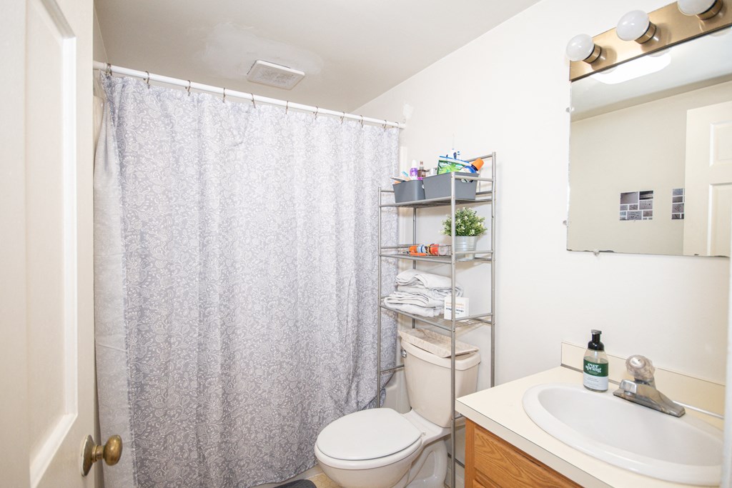 a bathroom with a white shower curtain and a white sink