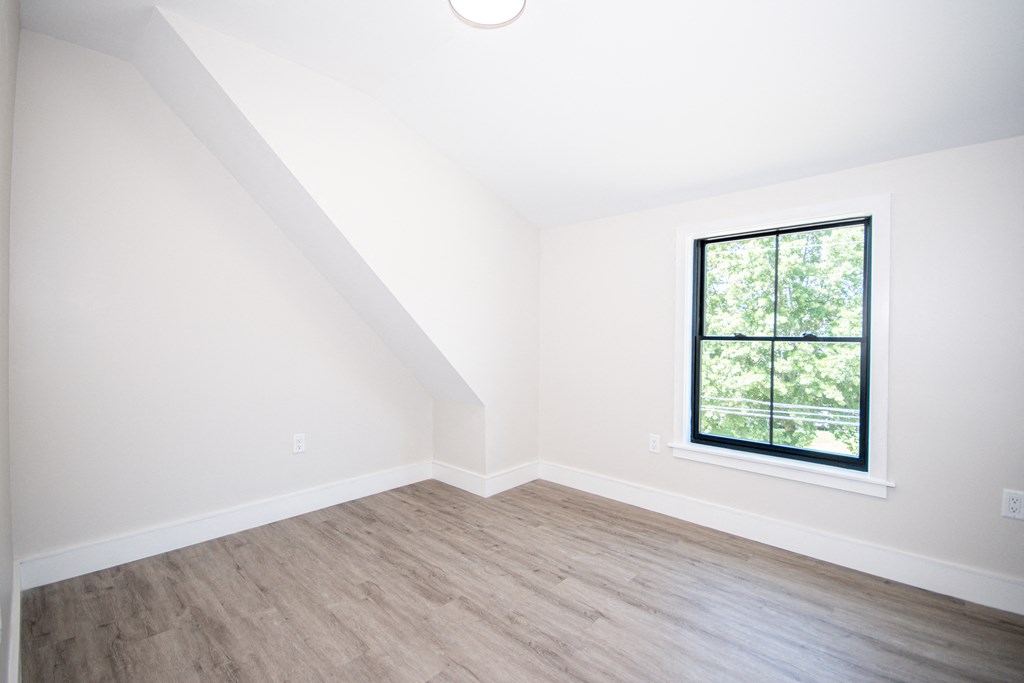 an empty bedroom with white walls and a large window