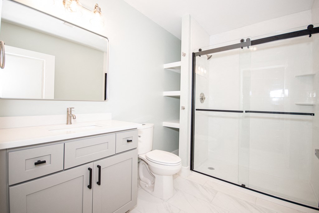a bathroom with a white sink and toilet next to a shower with a sliding glass door