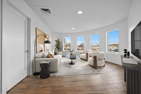 A living room with a white couch, a coffee table, and a large window.