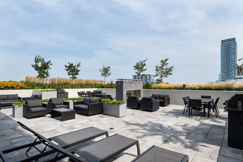 A rooftop patio with black furniture and a tall building in the background.