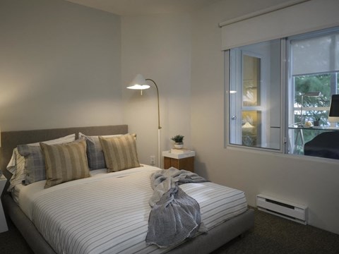 A bedroom with a large bed and a window overlooking a tree-filled area.