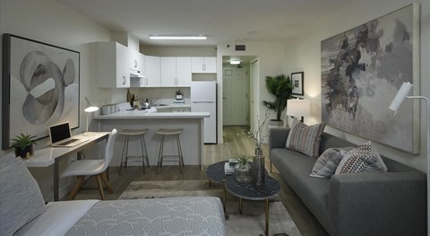 A modern living room with a grey couch and a kitchen in the background.