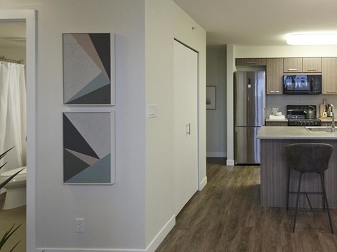A kitchen with a bar stool and a fridge.