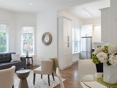 A modern living room with a grey couch, a white chair, and a round mirror on the wall.