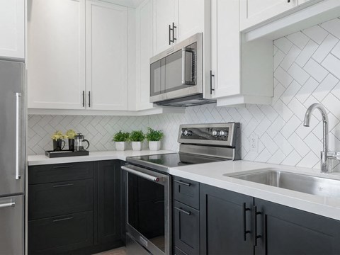 A kitchen with black cabinets and a stainless steel oven.