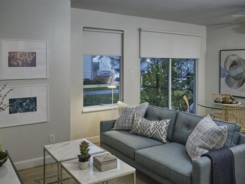 A living room with a grey couch and a small table with a plant on it.