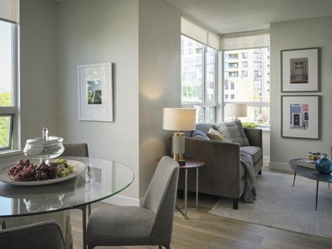 A living room with a glass table and grey chairs.
