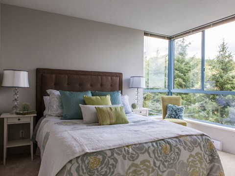 A bedroom with a large bed and a window overlooking a forest.