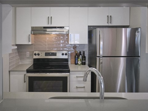 A modern kitchen with a stainless steel refrigerator and a stove top oven.