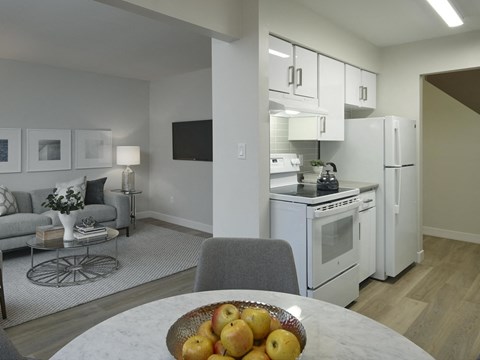 A kitchen with white appliances and a grey chair.
