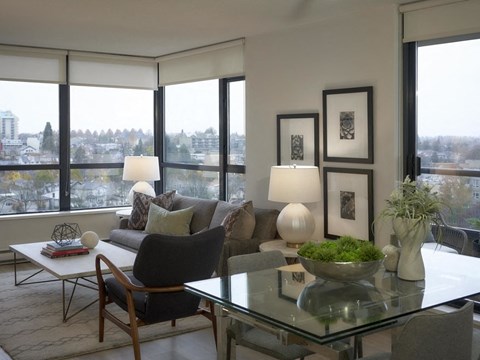 A modern living room with a glass table and a view of the city.