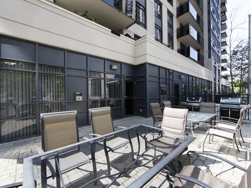 a patio with chairs and tables in front of a building