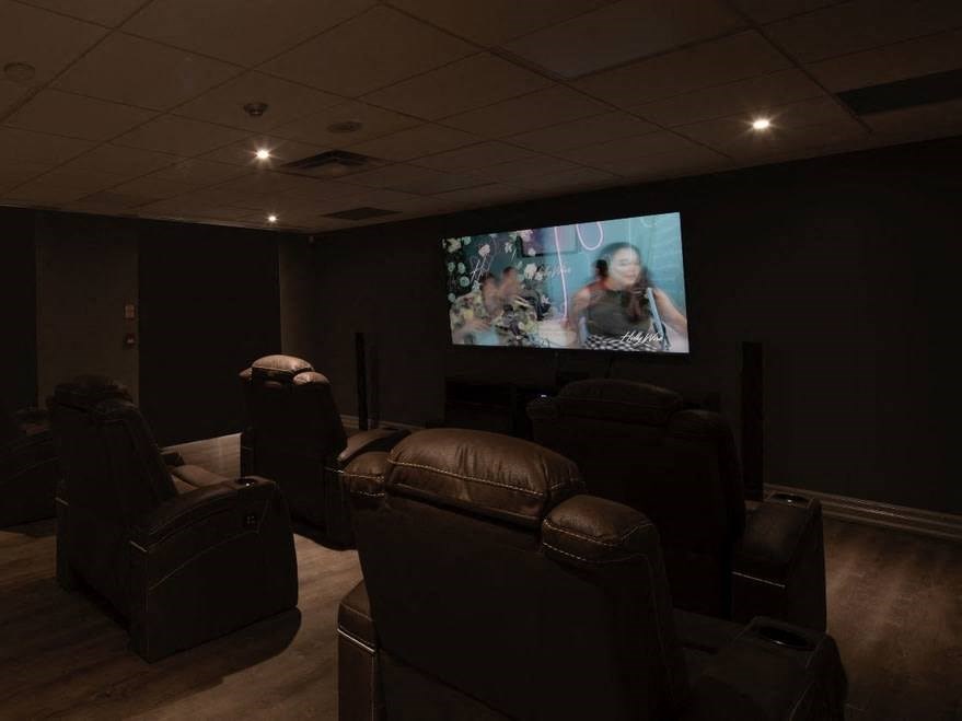 a home cinema room with leather chairs and a flat screen tv