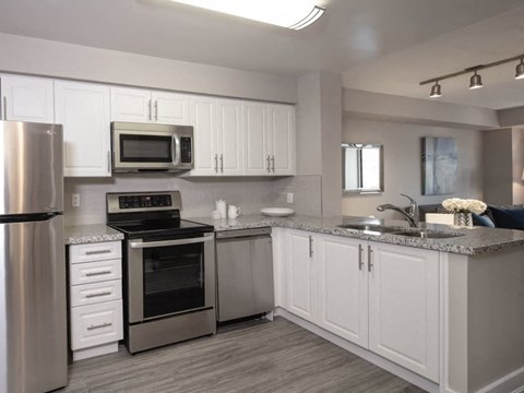 A modern kitchen with white cabinets and stainless steel appliances.