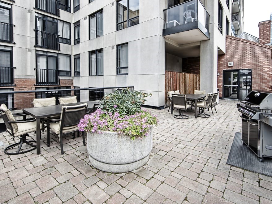 a patio with a grill and tables and chairs